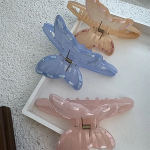 Detail of three resin butterfly hair claws with ribbon edges in amber blue and pink