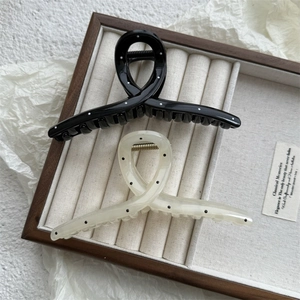 Close-up of elegant polka dot hair claws in black and cream in a wooden display box