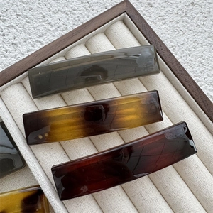 Detail view of rectangular tortoise shell hair clips in a wooden display box