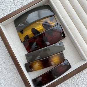Detailed top view of six colorful rectangular hair clips in a wooden velvet display case