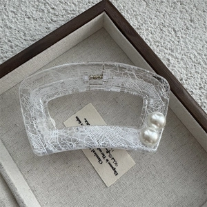 Détail d'une pince à cheveux carrée transparente avec motif dentelle et perles doubles