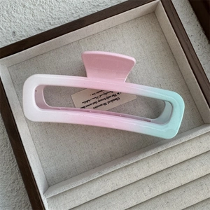 Detailed view of large pink and green gradient hair claw clip with a matte finish texture