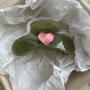 Detail of olive green jelly hair claw clip with a pink heart on white paper background