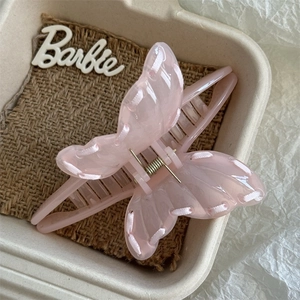 Detailed shot of a pink butterfly hair claw with ribbon trim on natural linen texture