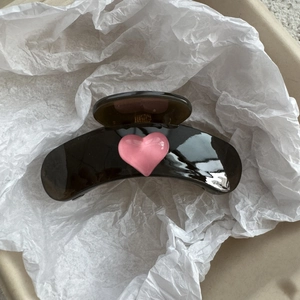 Close-up of a brown translucent claw clip featuring a 3D pink heart on a white background