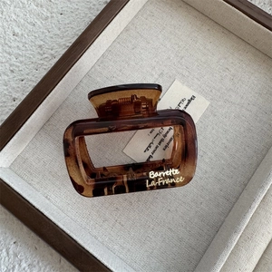 Detailed macro view of an amber patterned rectangular hair claw clip with golden text