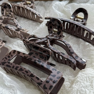 Close-up of assorted leopard print hair claws in rectangle and bow shapes on white paper