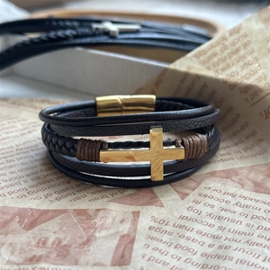 Detail of multi-layer black leather bracelet with golden cross and magnetic clasp