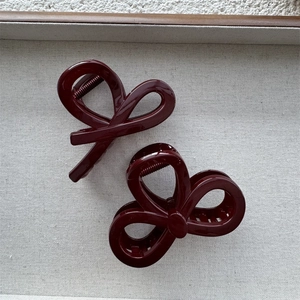 Glossy wine red thick shark hair clips with elegant bow design on a minimalist tray