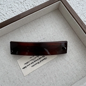 Close-up of tortoise shell pattern acrylic hair clip on a vintage linen background