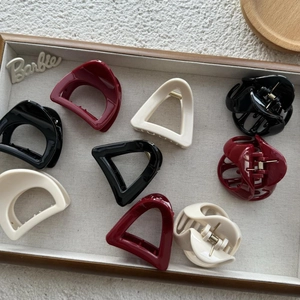 Close-up of geometric hollow hair claws in matte black, burgundy and cream white colors