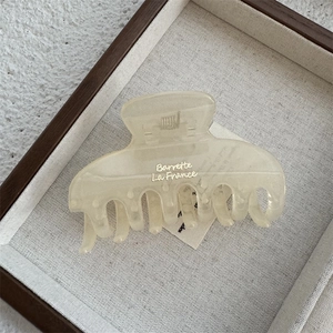 Detail view of the cream hair claw clip with golden Barrette La France text engraving