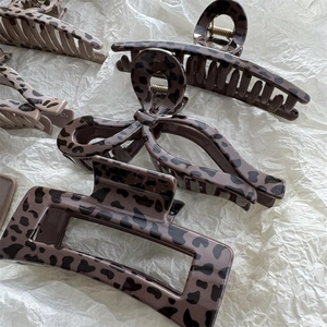 Minimalist leopard print hair claws in bow and rectangle shapes on textured paper