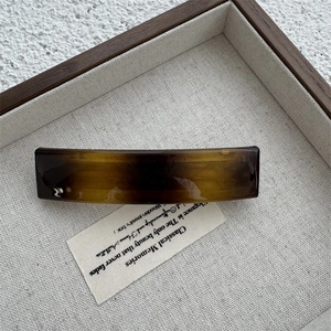 Detail shot of the amber tortoiseshell hair clip on a display tray for women