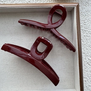 Macro shot of dark burgundy hair claws in a wooden tray with glossy finish details