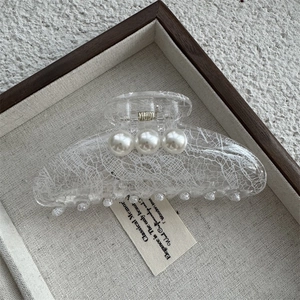 Détail d'une pince à cheveux en dentelle transparente ornée de trois grandes perles blanches