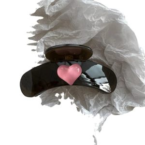 Glossy dark Korean heart hair claw clip on textured white paper background