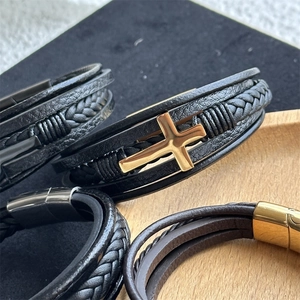Detailed view of multilayer leather bracelet featuring a gold cross and magnetic buckle