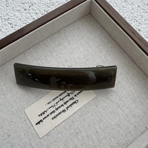 Detail of elegant dark brown amber hair clip on a wooden display tray with linen base