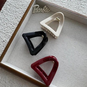 Three minimalist triangular hair claws in cream, black, and dark red glossy finish