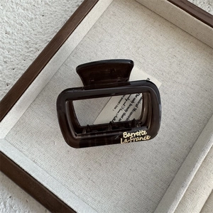 Close-up of translucent dark brown square hair claw clip with gold lettering