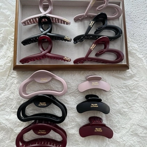 Close-up of matte cloud hair claws in pink and black with golden brand lettering