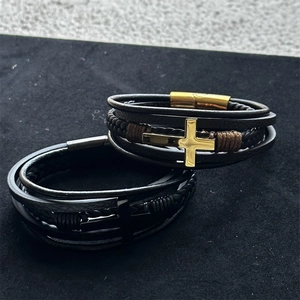 Close-up of multilayer braided leather bracelet with golden cross and magnetic clasp