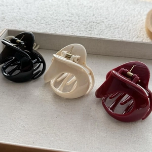 Close-up of three triangle hair claws in black, cream, and red on a velvet tray