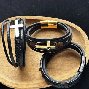 Close-up of three-piece men's leather bracelets with silver and gold stainless cross charms