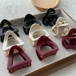 Close-up of hollow triangle and semicircle hair claws in black, cream, and wine red colors