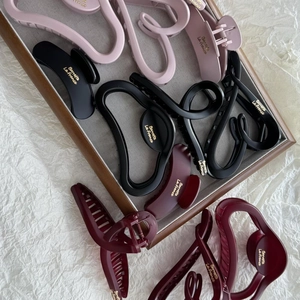 Matte finish large hair claws with golden logo branding in pastel pink and black colors