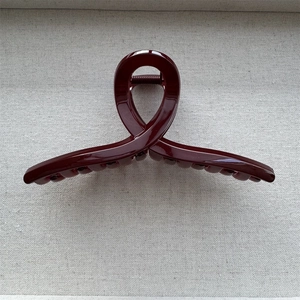 Detail showing high-gloss burgundy hair claw clip with interlocking teeth for styling