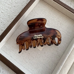 Detail view of a French style tortoiseshell hair claw clip with golden text engraving