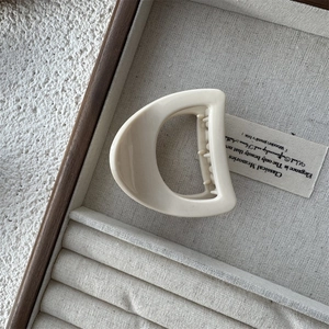 Detailed close-up of a cream hollow D-shape hair claw clip with internal teeth