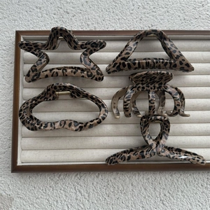 Detail view of five assorted leopard print hair claw clips on a velvet display board