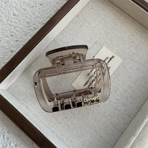 Macro view of a brown translucent resin square claw clip with gold cursive lettering