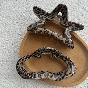 Close-up of leopard print star and oval hair claws on a wooden tray with gold springs