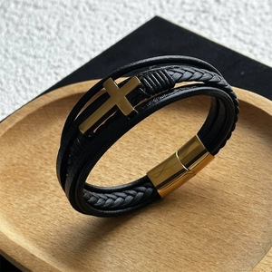 Detail of multi-layer braided black leather bracelet with gold cross and magnetic clasp