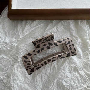 Detail of a large square leopard print hair claw clip in creamy beige and dark spots