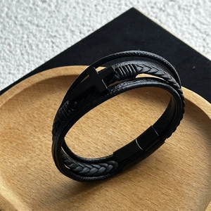 Close-up of men's multi-layer braided leather bracelet with black cross and magnetic clasp