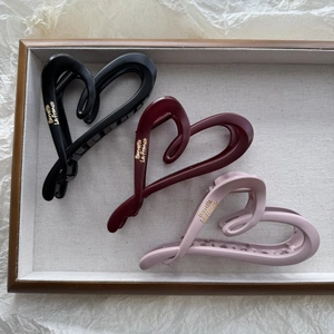 Three matte heart-shaped hair claws in black, burgundy, and pink with gold lettering