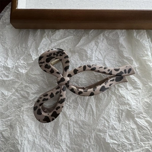 Close-up of leopard print bow hair claw clip with golden metal spring on white paper