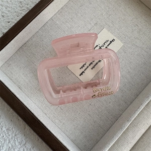 Detail of pink translucent rectangular hair claw clip with golden Barrette France text