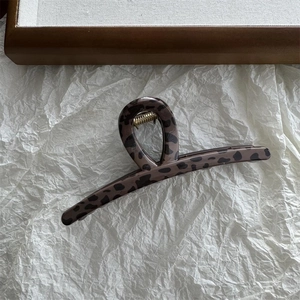 Macro detail of leopard print hair claw clip with golden spring on textured background