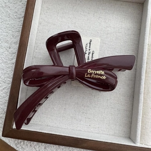Detail view of burgundy resin bow hair claw with gold Barrette La France lettering