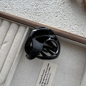 Detail of a glossy black hollow triangle hair claw clip on a gray velvet jewelry tray