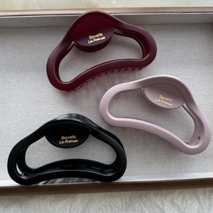 Three premium matte hair claws in burgundy, pink, and black colors on a tray