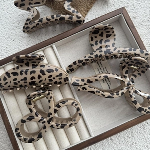 Détail de quatre pinces à cheveux à motif léopard beige sur un plateau en bois vintage