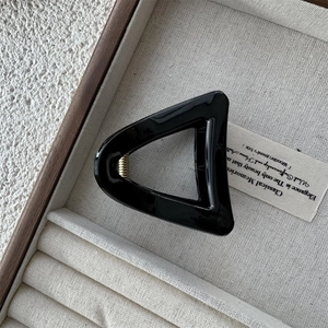 Macro shot of minimalist black hollow triangle hair claw clip in a velvet jewelry box