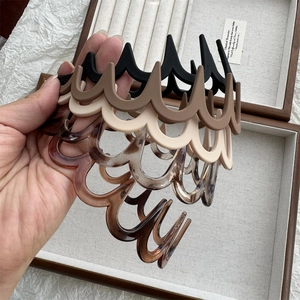 Détail de pinces à cheveux ondulées en résine noire, ambre et crème sur tissu